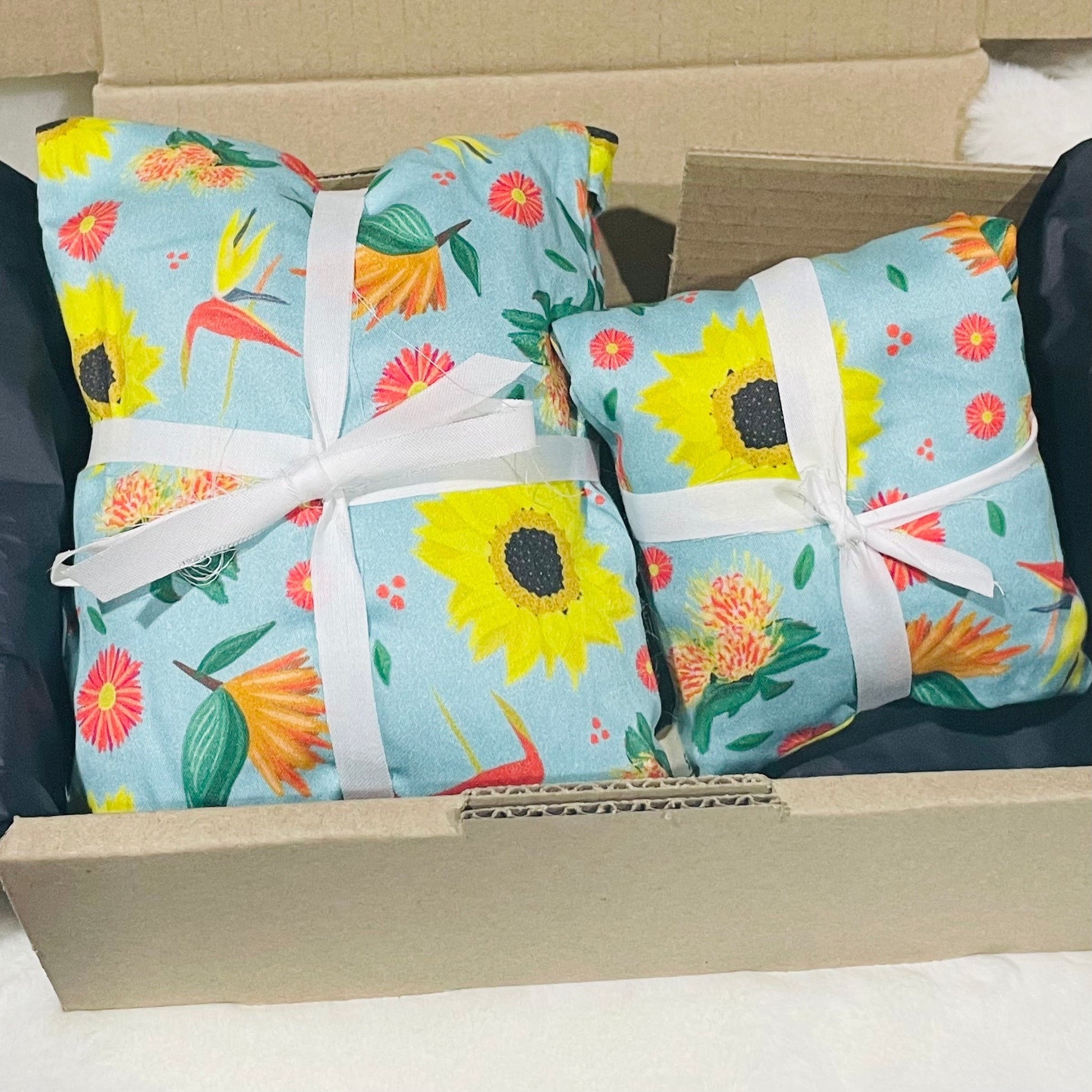 Sherrie Morgan Design 'Bright & Breezy' Australian Wheat heat & eye pillow set, the print comprises of sunflowers, orange birds of paradise flowers and other colourful flora on a light sky blue fabric.