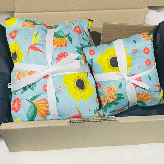 Sherrie Morgan Design 'Bright & Breezy' Australian Wheat heat & eye pillow set, the print comprises of sunflowers, orange birds of paradise flowers and other colourful flora on a light sky blue fabric.