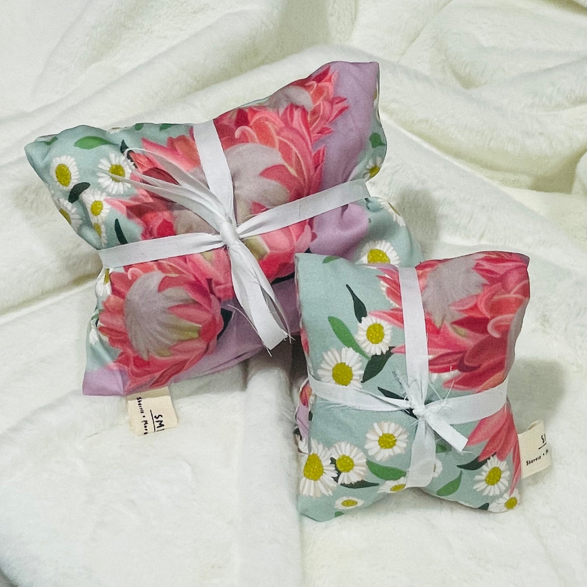 Sherrie Morgan Design 'Ribbons' Australian Wheat heat & eye pillow set, the print comprises of pink king protea flowers and daisies on a light blue background.