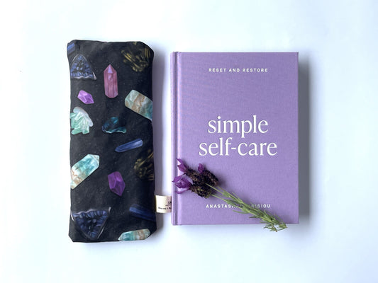 Sherrie Morgan Design relaxing eye pillow with a crystal and cosmic looking design, shown with a relaxing book.