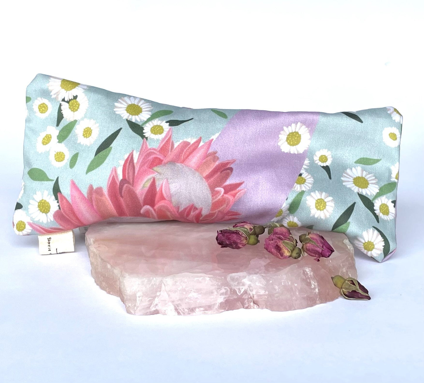 Sherrie Morgan Design relaxing eye pillow with a soft protea and daisy flower print in pink and turquoise, pictured with a rose quartz stone