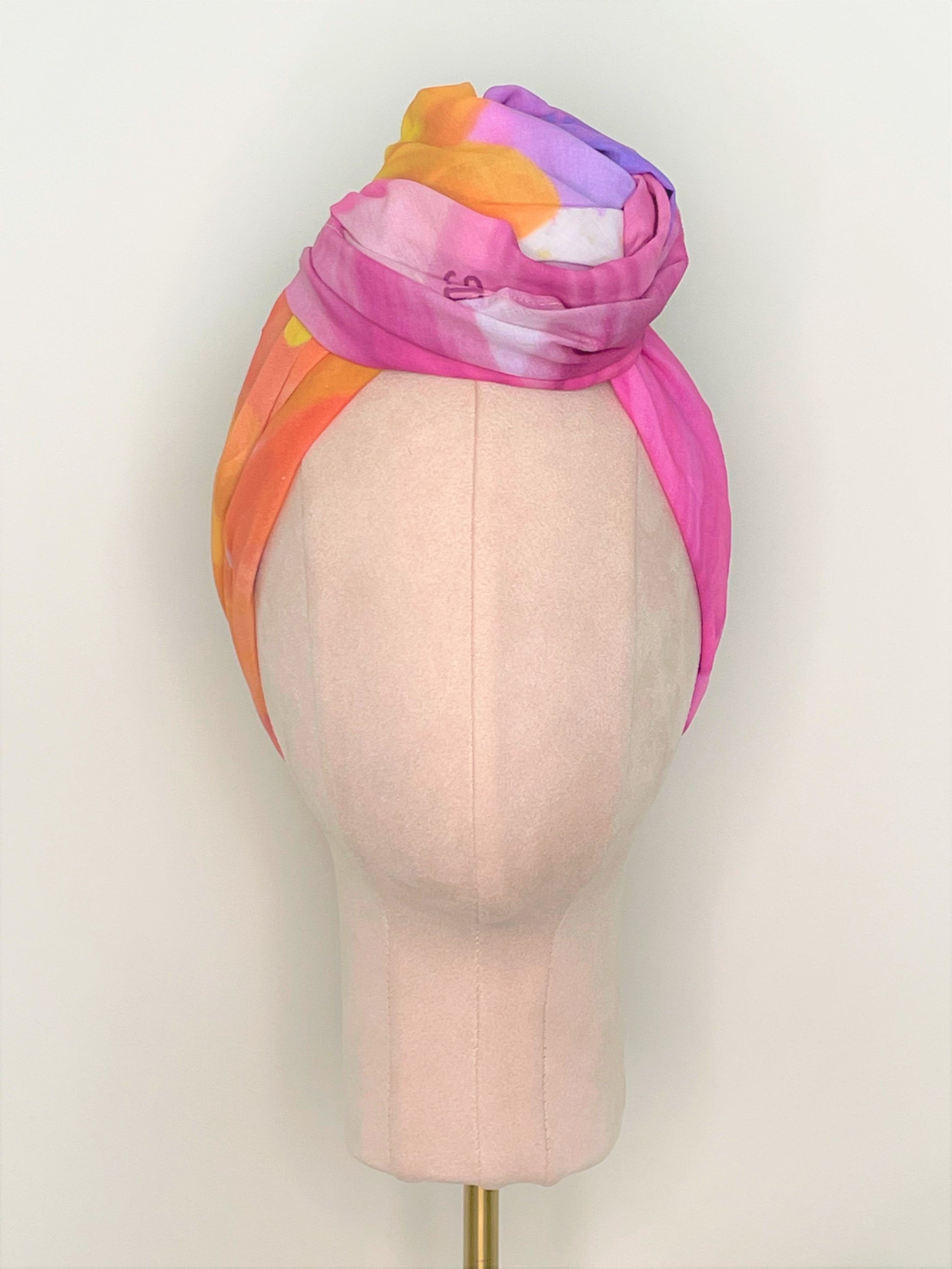 SMD Original art 'Blossom', a bright multicoloured floral design, displayed as a head wrap with a large twisted knot, front view