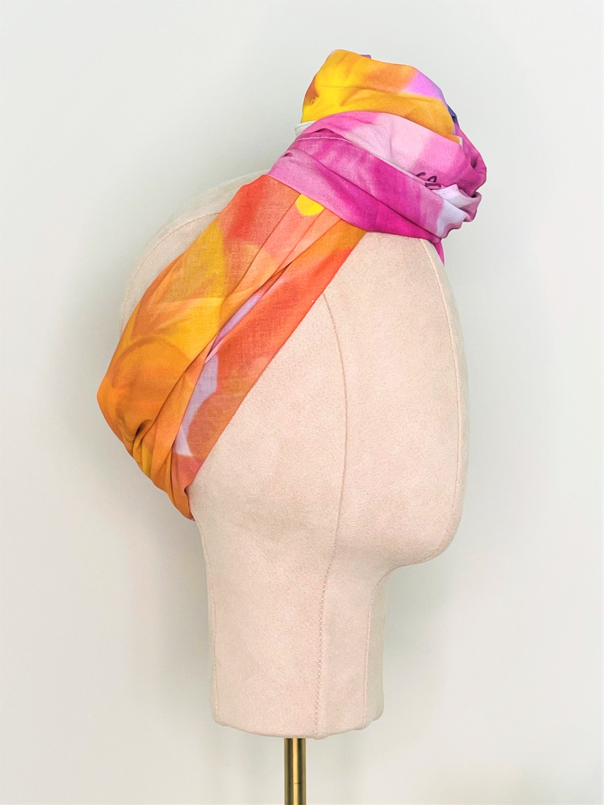 SMD Original art 'Blossom', a bright multicoloured floral design, displayed as a head wrap with a large twisted knot, side view