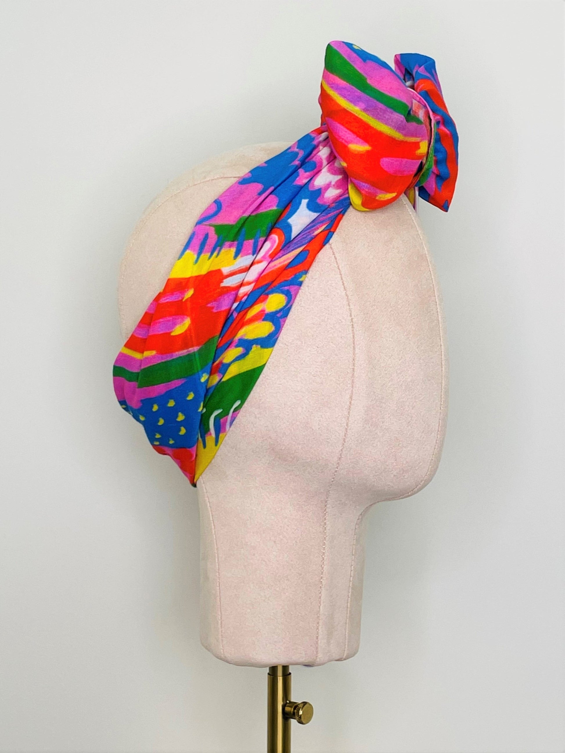 SMD scarf, bright colourful abstract lines pattern, red, yellow, blue, green, pink, shown as headwrap with large bow, design Katie Kortman, side view