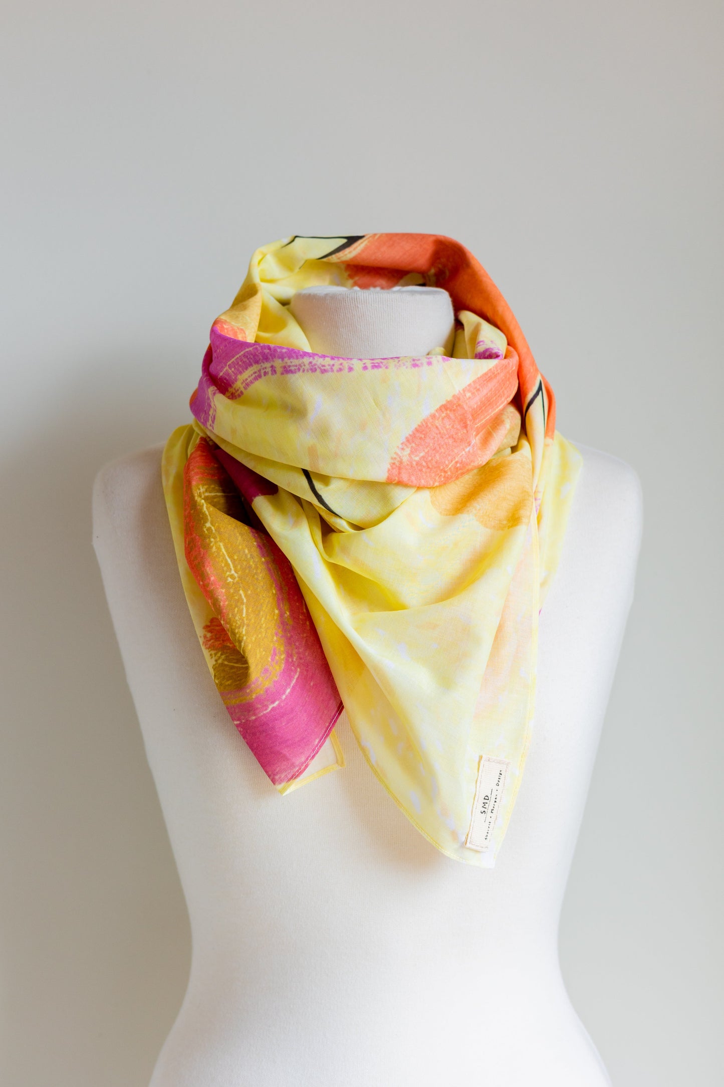 Original Sherrie Morgan design 'Desert Rainbow', comprises a yellow setting with rainbows and shapes in brown, pink and orange, displayed as a neckscarf.