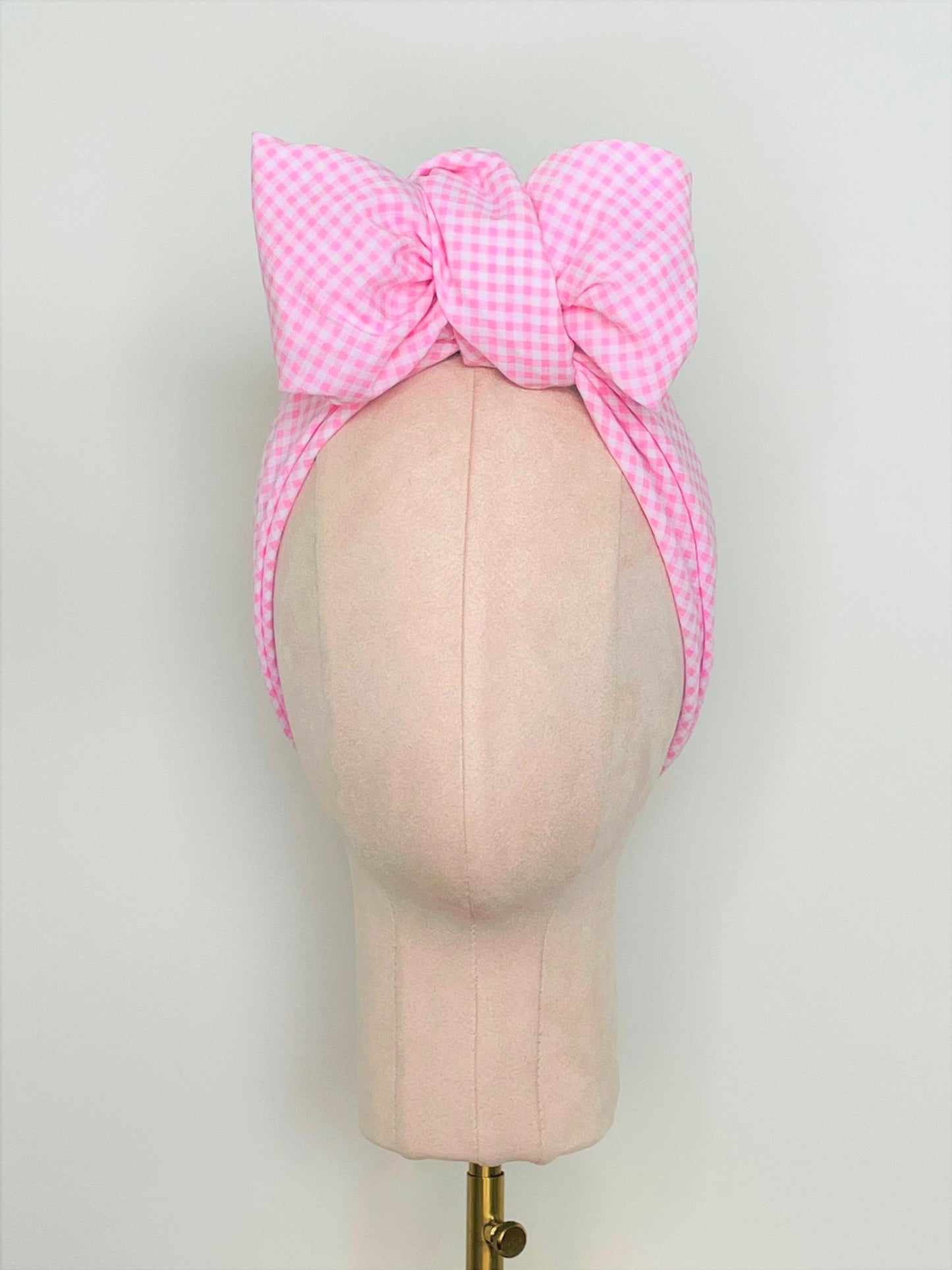 SMD scarf, upcycled pink checkers or gingham fabric, displayed as a headscarf with a bow, front view