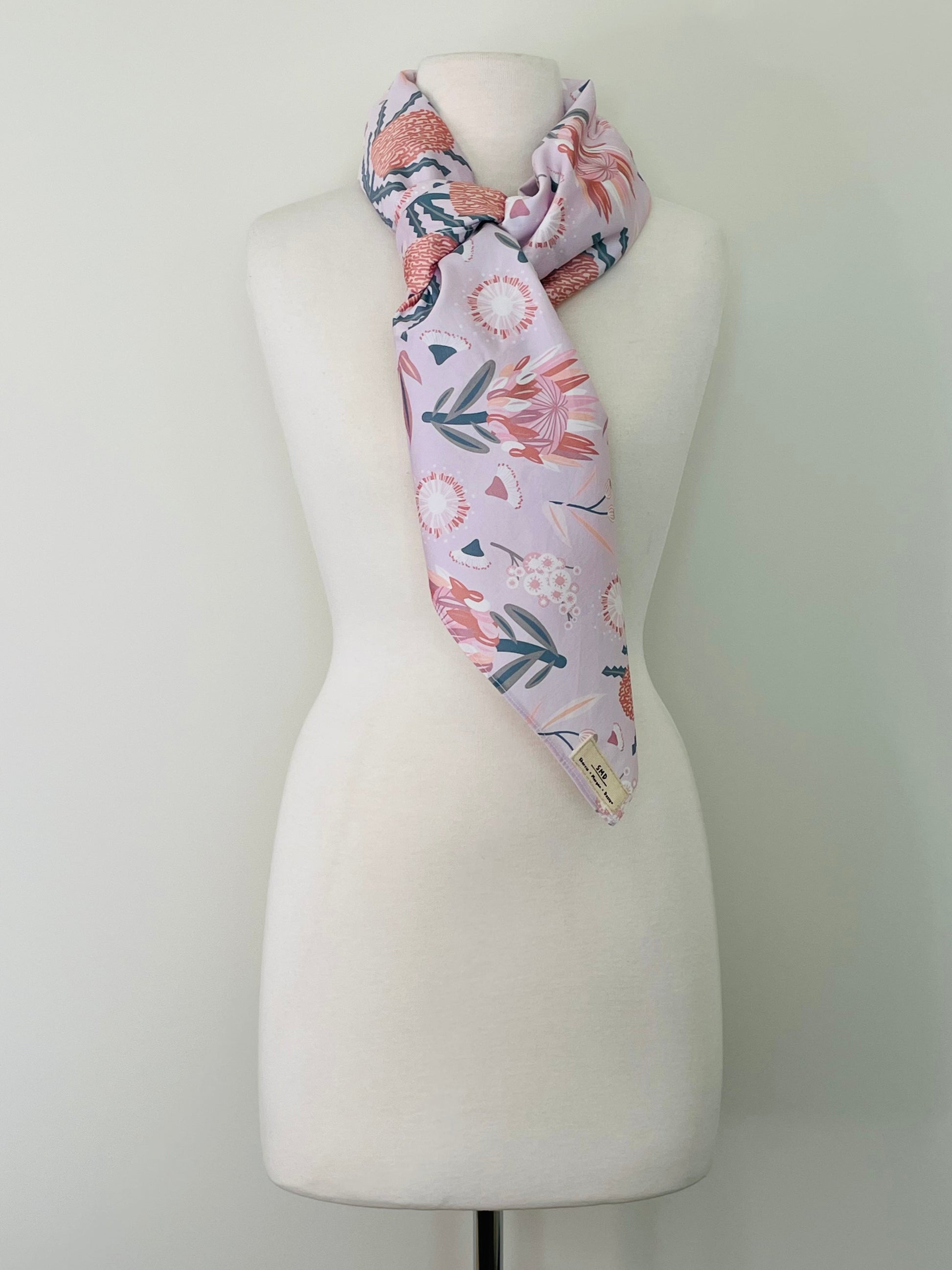 SMD scarf, Christie Williams design of pink proteas and banksia on pink base, displayed as a neck scarf