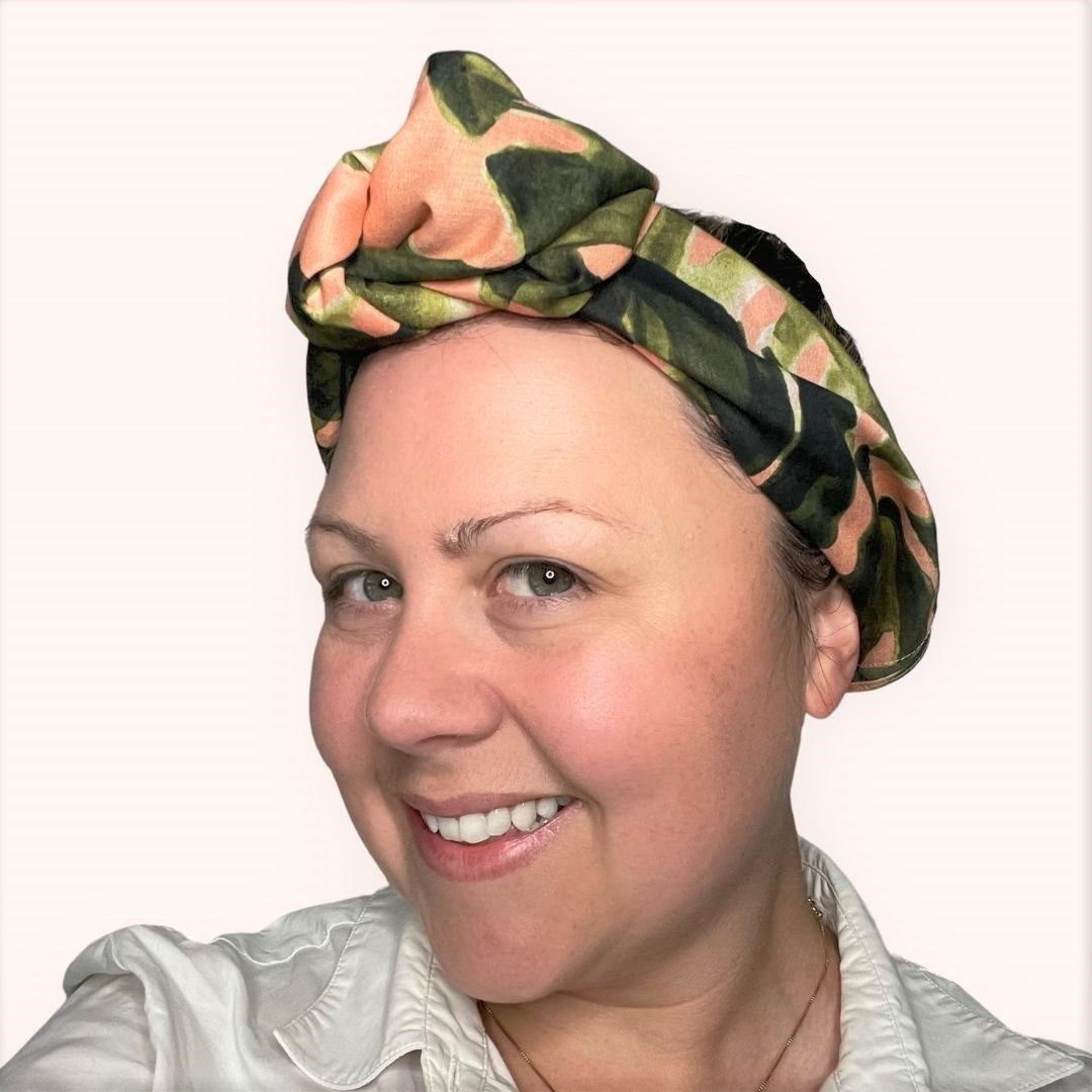 SMD scarf, large monstera leaves design by Australian designer Nerida Hansen on apricot base, shown as headwrap with large knot, side view