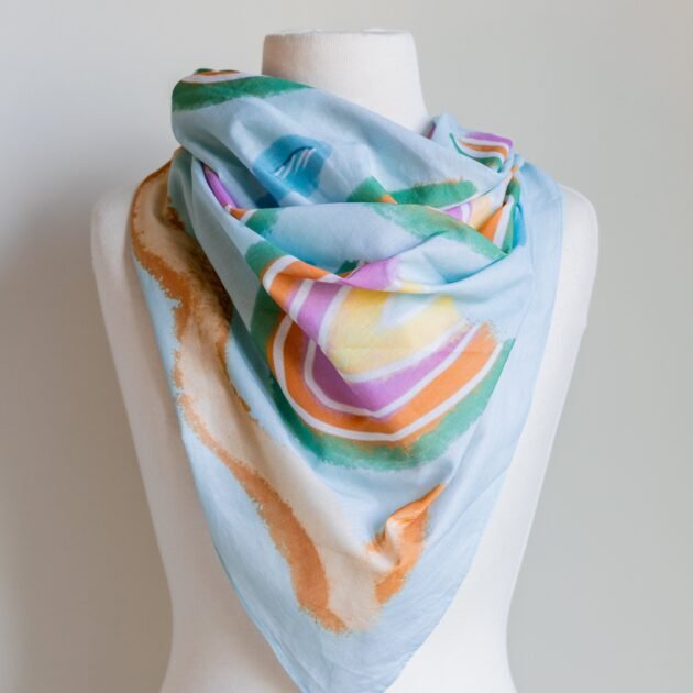SMD original art 'Rain or Shine', light blue base with rainbows and rain, displayed as a neck scarf