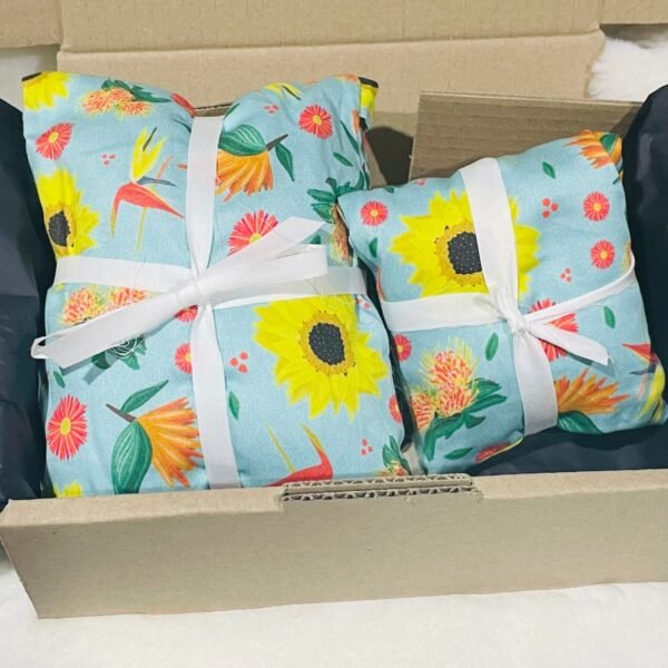 Sherrie Morgan Design 'Bright & Breezy' Australian Wheat heat & eye pillow set, the print comprises of sunflowers, orange birds of paradise flowers and other colourful flora on a light sky blue fabric.