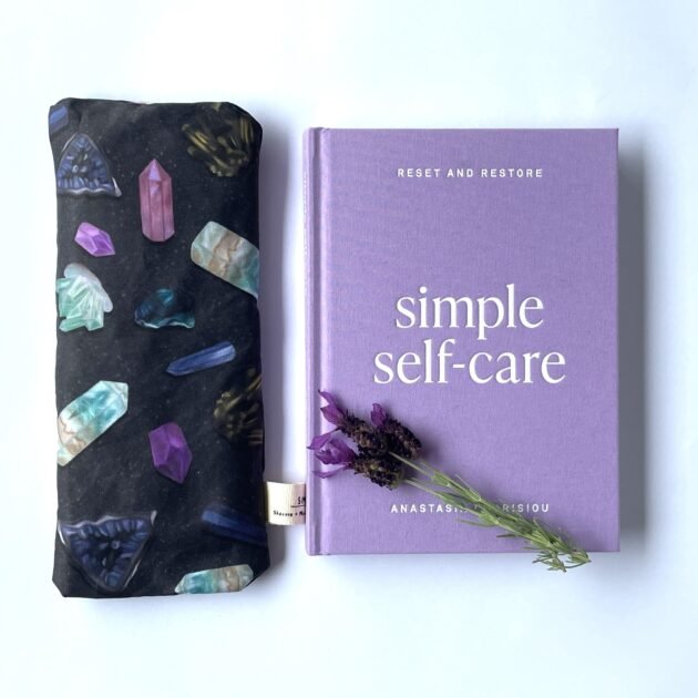 Sherrie Morgan Design relaxing eye pillow with a crystal and cosmic looking design, shown with a relaxing book.
