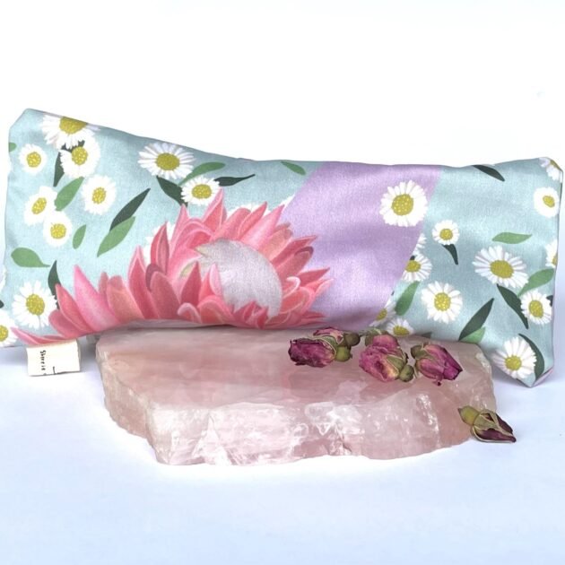 Sherrie Morgan Design relaxing eye pillow with a soft protea and daisy flower print in pink and turquoise, pictured with a rose quartz stone