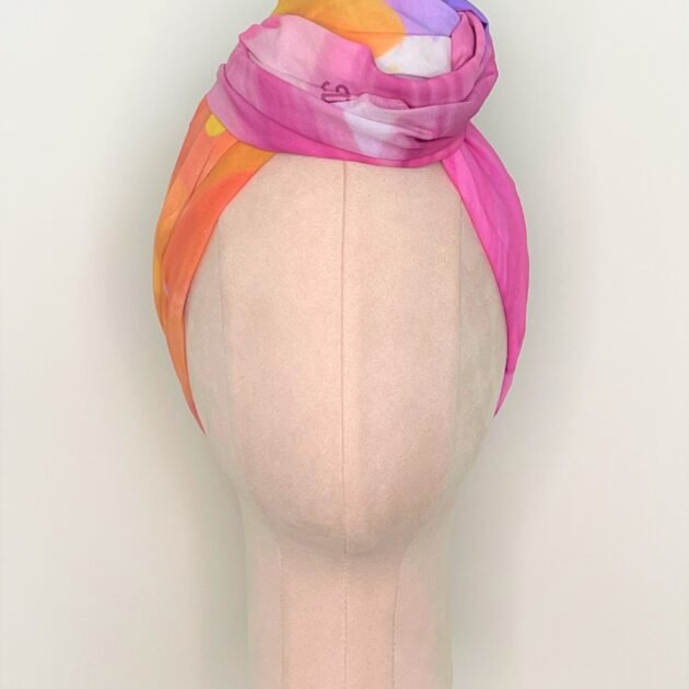 SMD Original art 'Blossom', a bright multicoloured floral design, displayed as a head wrap with a large twisted knot, front view