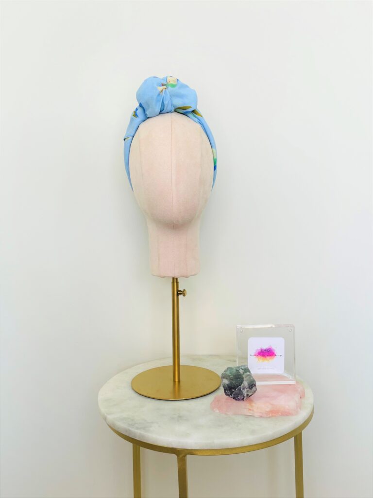 SMD scarf, design by Margaret Jeane,  pears on blue base, scarf displayed as headwrap with top knot, front view