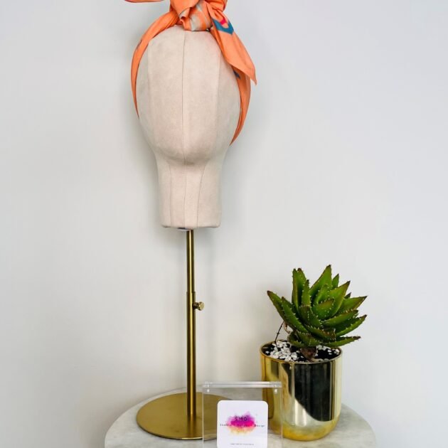 SMD original digital art 'Cheeky', a blue winking face on an apricot base, shown as a headband with side tie, front view