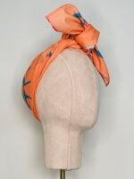 SMD original digital art 'Cheeky', a blue winking face on an apricot base, shown as a headband with side tie, side view