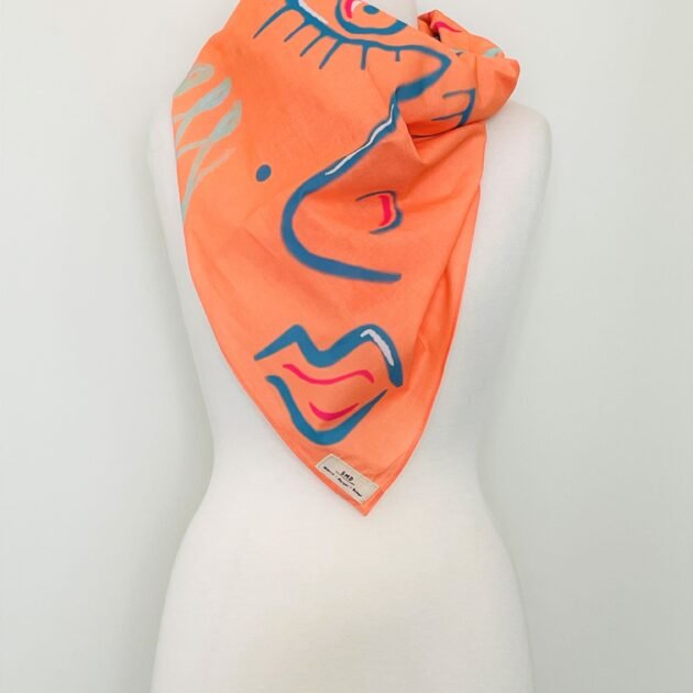 SMD original digital art 'Cheeky', a blue winking face on an apricot base, shown here as a neck sacrf