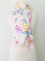 SMD scarf, colourful monstera leaves on a white base, shown as neck scarf