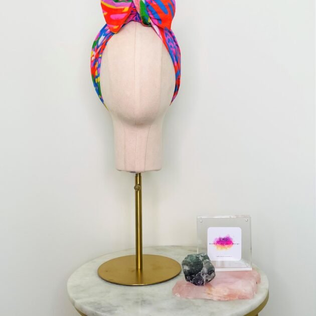 SMD scarf, bright colourful abstract lines pattern, red, yellow, blue, green, pink, shown as headwrap with large bow, design Katie Kortman, front view