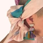 SMD original art scarf, pastel pink with green and blue shapes and abstract design, shown as headscarf with low side bow close up