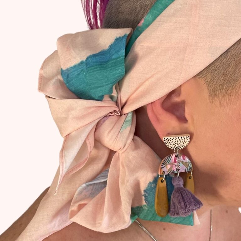 SMD original art scarf, pastel pink with green and blue shapes and abstract design, shown as headscarf with low side bow close up