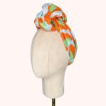 SMD original art 'Eye of the', animal print in red and green, displayed as a headwrap with a large knot, side view.