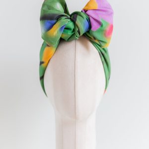 SMD original art 'Flowers for Days', multi coloured flowers in a grassy green field, displayed as headwrap with a large bow, front view.