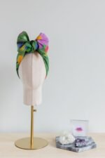 SMD original art 'Flowers for Days', multi coloured flowers in a grassy green field, headwrap with a large bow, pictured with a crystal and business card.