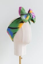 SMD original art 'Flowers for Days', multi coloured flowers in a grassy green field, displayed as headwrap with a large bow, side view.