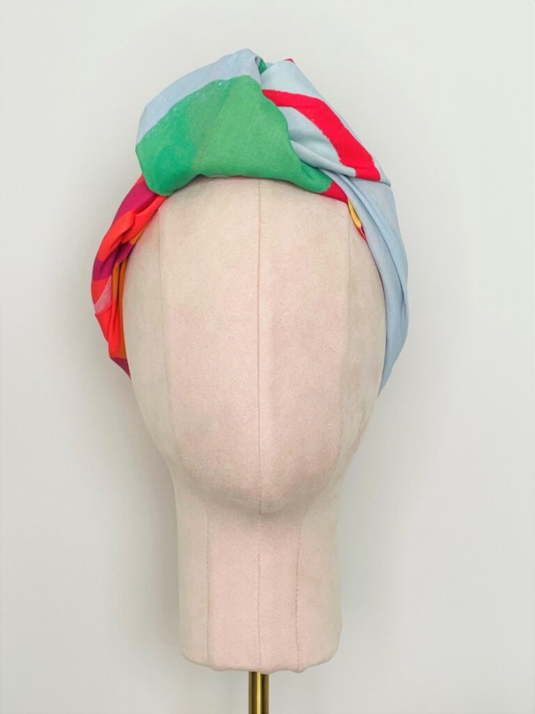 Sherrie Morgan Design original art, colourful large fruit design, yellow, orange, green, blue, red. Shown here as a knotted headscarf. Front view.