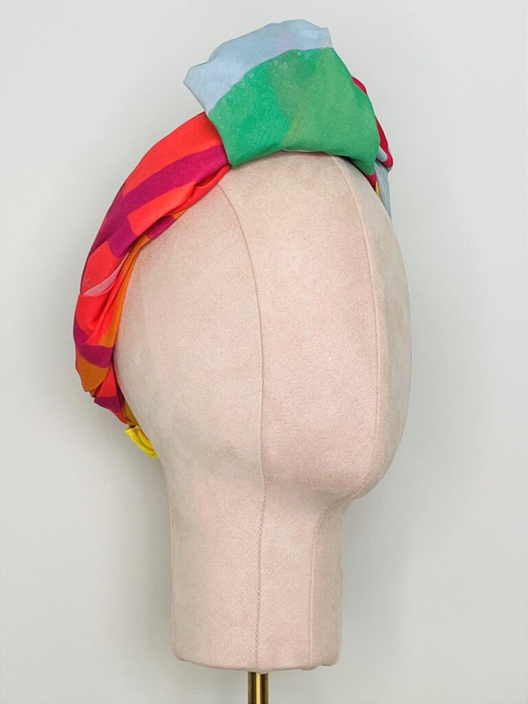 Sherrie Morgan Design original art, colourful large fruit design, yellow, orange, green, blue, red. Shown here as a knotted headscarf, Side view.