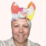 Sherrie Morgan Design original art, colourful large fruit design, yellow, orange, green, blue, red. Shown here as a large bow headscarf, Front view.