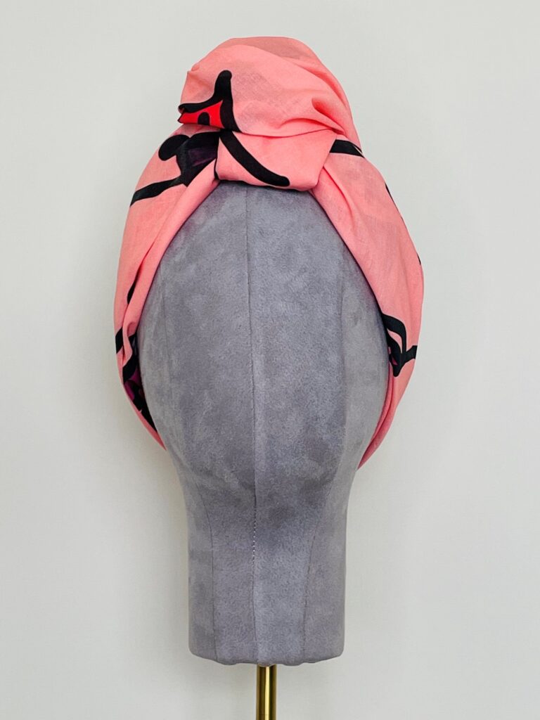 SMD original art 'Hey There', featuring a winking face with red lips on a pink base, displayed as head turban, front view