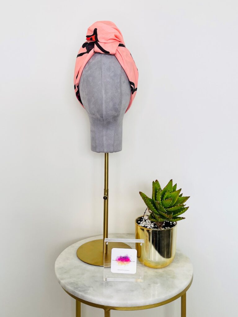 SMD original art 'Hey There', featuring a winking face with red lips on a pink base, displayed as head turban, front view, lifestyle