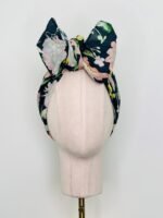 SMD scarf, navy base with a multicoloured floral sea print, shown as a headband with large bow, front view