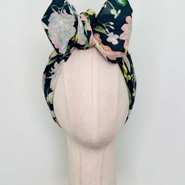 SMD scarf, navy base with a multicoloured floral sea print, shown as a headband with large bow, front view