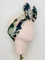 SMD scarf, navy base with a multicoloured floral sea print, shown as a headband with large bow, side view