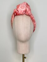 SMD scarf, Emma Stenhouse design in orange, displayed as a headwrap with top knot, front view