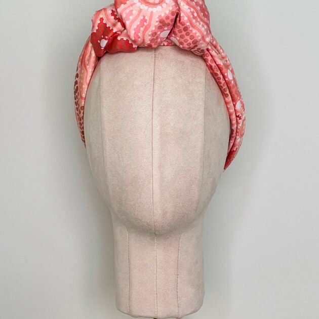 SMD scarf, Emma Stenhouse design in orange, displayed as a headwrap with top knot, front view