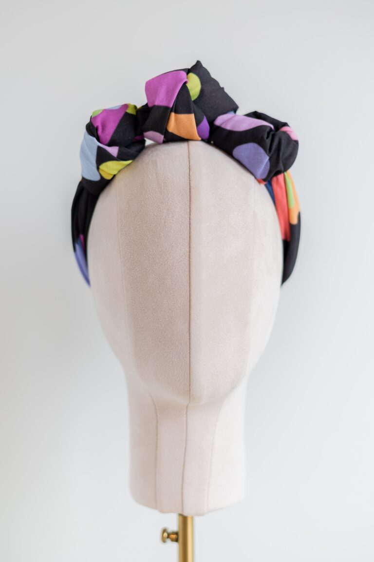 smd orginal 'party popper' scarf, black base with bright colourful shapes resembling confetti, shown here in a head crown style, front view