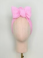 SMD scarf, upcycled pink checkers or gingham fabric, displayed as a headscarf with a bow, front view