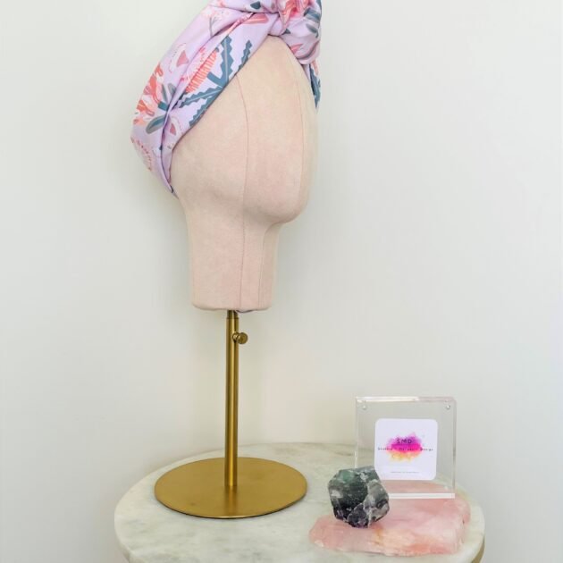 SMD scarf, Christie Williams design of pink proteas and banksia on pink base, displayed as a headscarf with top knot, side view