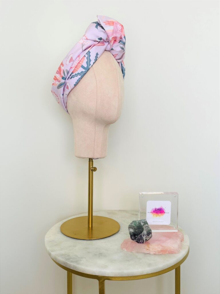 SMD scarf, Christie Williams design of pink proteas and banksia on pink base, displayed as a headscarf with top knot, side view