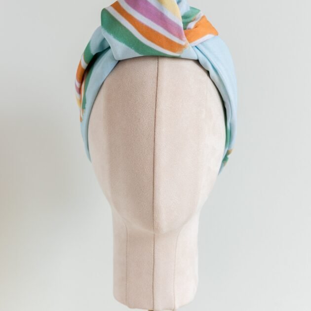 SMD original art 'Rain or Shine', light blue base with rainbows and rain, displayed as a headscarf with flat knot, front view
