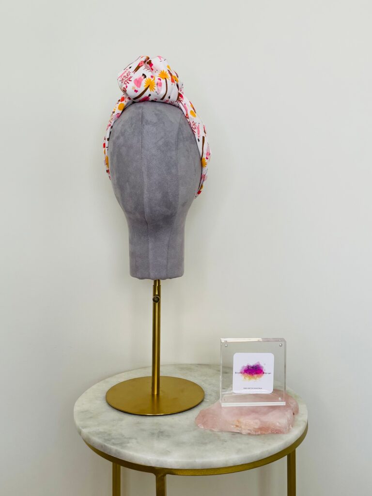 SMD scarf, white base with ladies and dogs walking in pink and yellow, knotted headscarf, front view