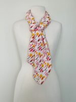 SMD scarf, white base with ladies and dogs walking in pink and yellow, shown as neck scarf